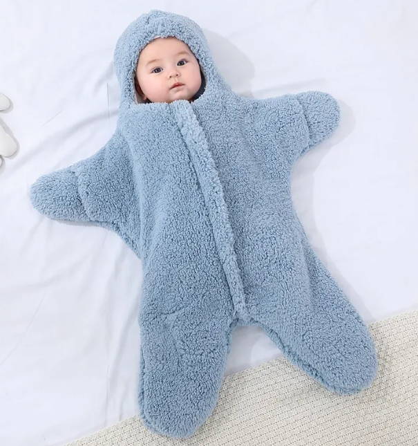 Baby in a blue hooded fleece starfish-shaped baby quilt sleep sack, front view