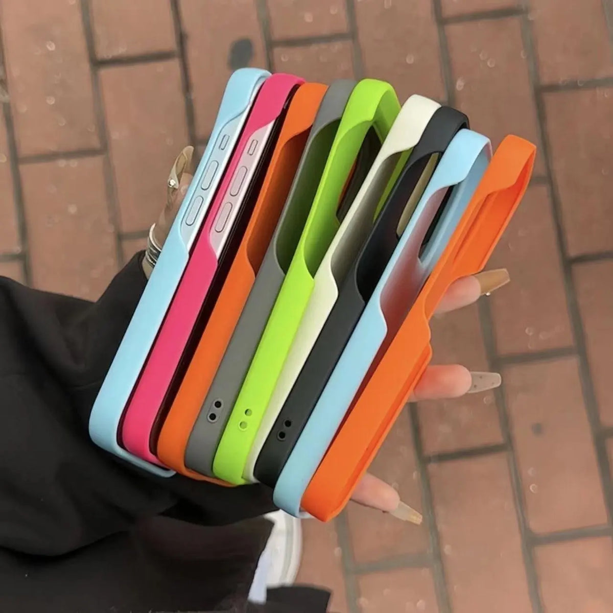 Stack of half-pack graphite phone cases in all colors held in hand