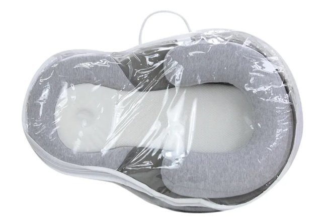 Gray anti-spit-up baby pillow in clear plastic packaging, front view