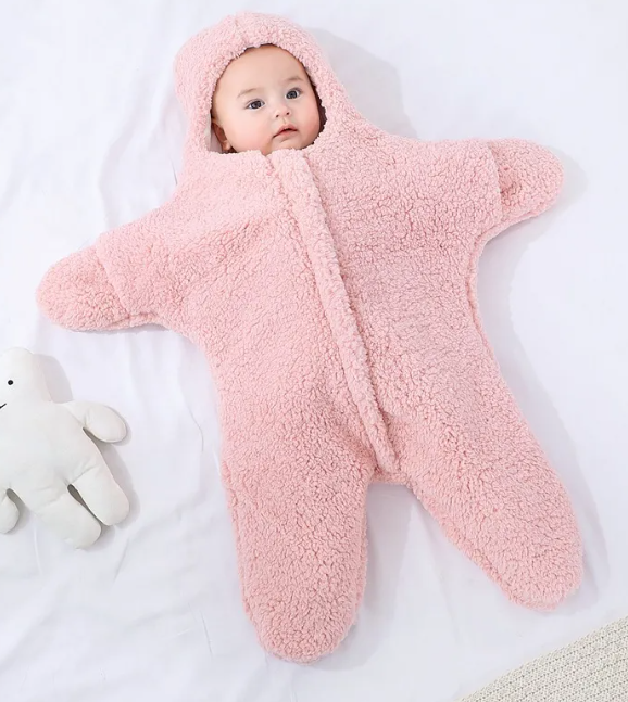 Baby in a pink hooded fleece starfish-shaped baby quilt sleep sack shown upright