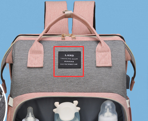 Close-up of the pink and gray mommy bag's top handle and label