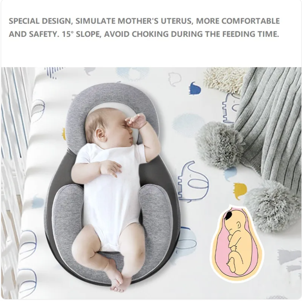 Baby lying in a gray anti-spit-up pillow on a crib mattress