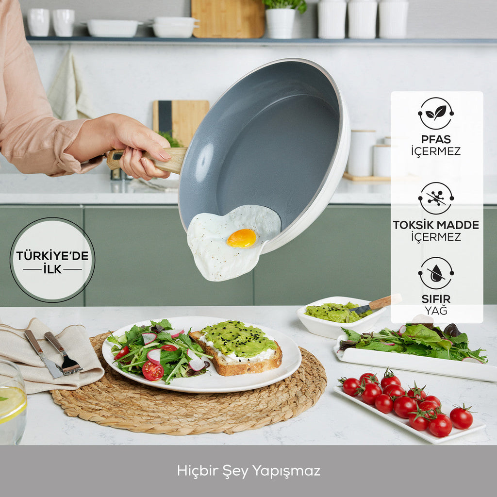 Egg sliding off a nonstick frying pan above a breakfast spread