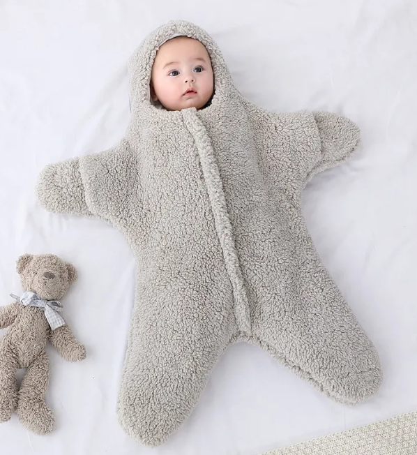 Baby in a gray hooded fleece starfish-shaped baby quilt sleep sack shown upright