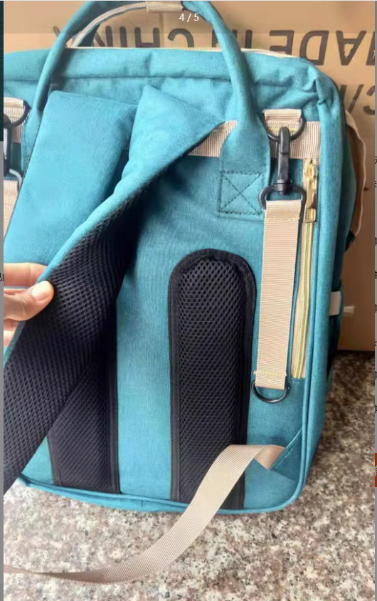 Opened teal mommy bag showing its fold-out bed compartment