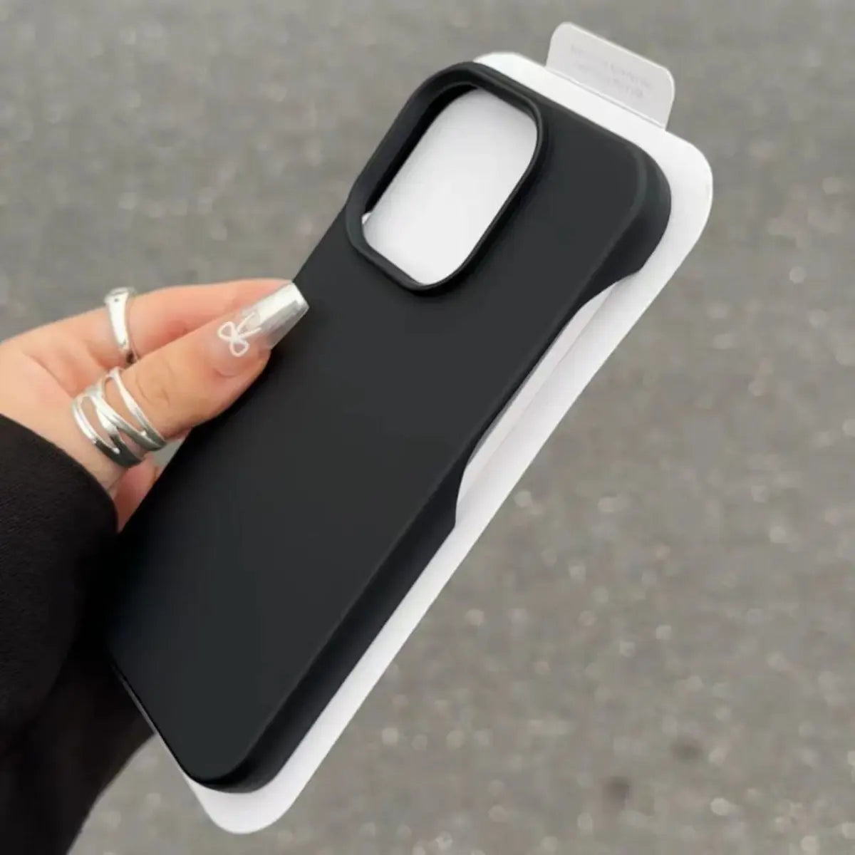 Hand holding a black half-pack graphite phone case with white backing, centered view