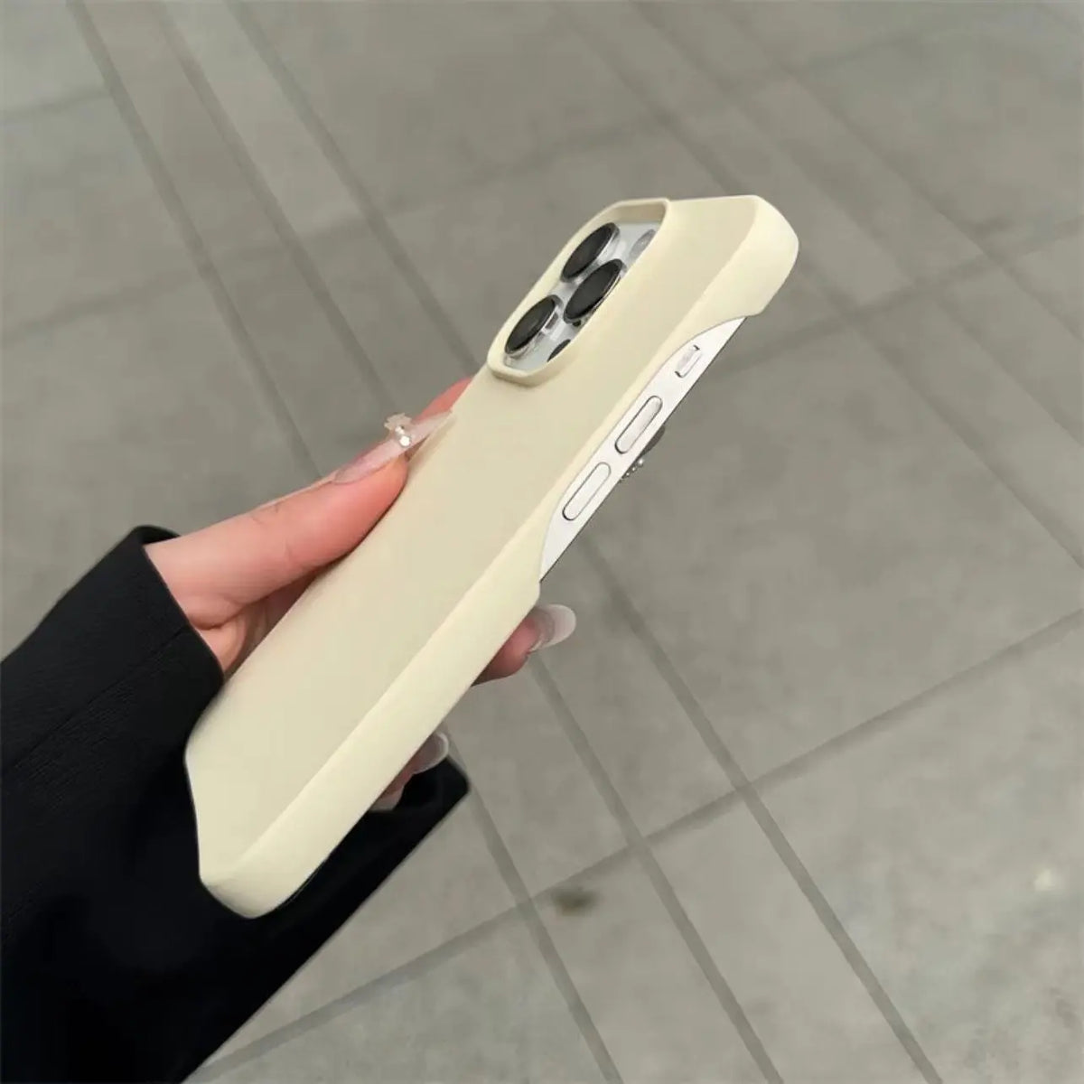 Hand holding a cream half-pack graphite phone case outdoors, product shot
