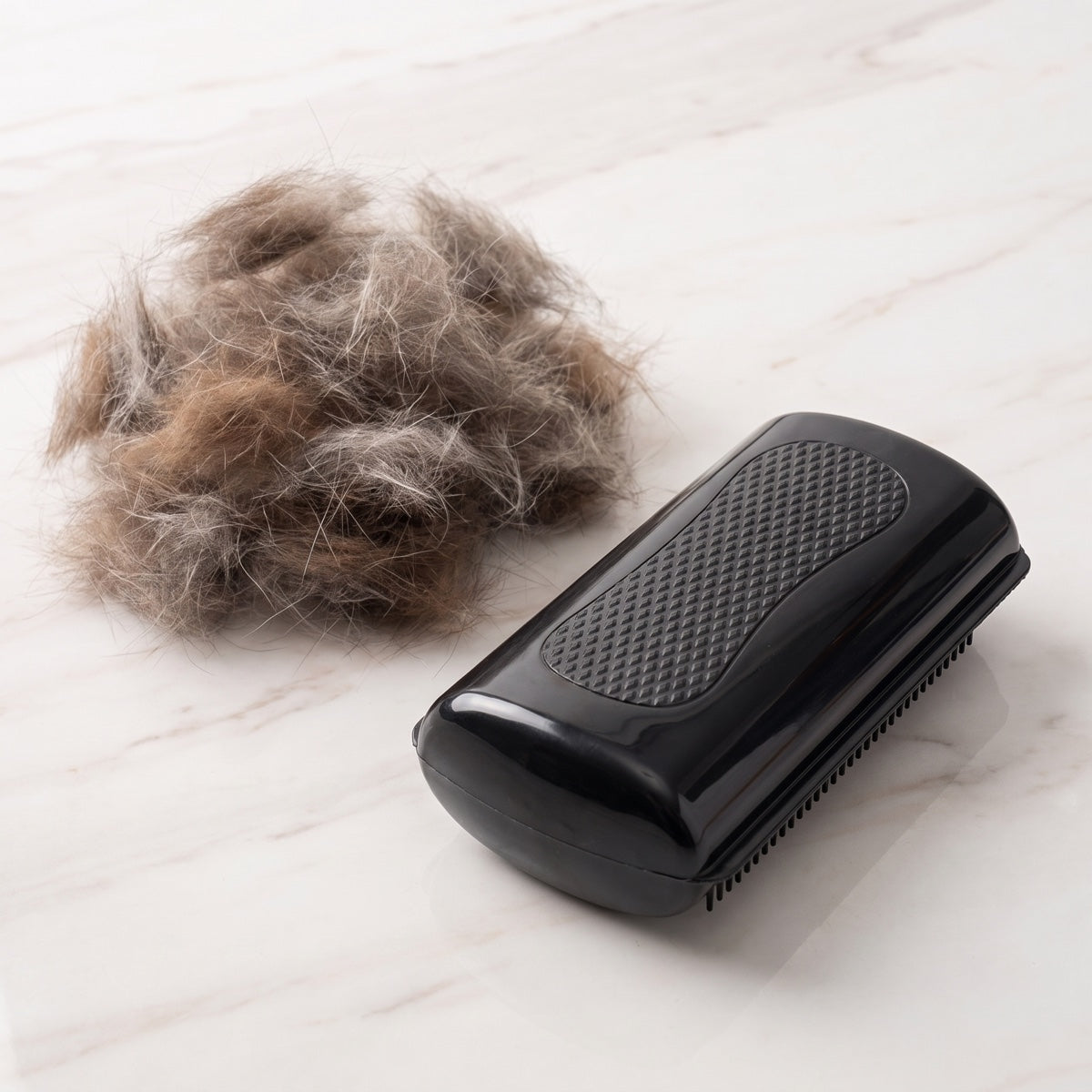 Black pet grooming comb next to a pile of removed pet hair