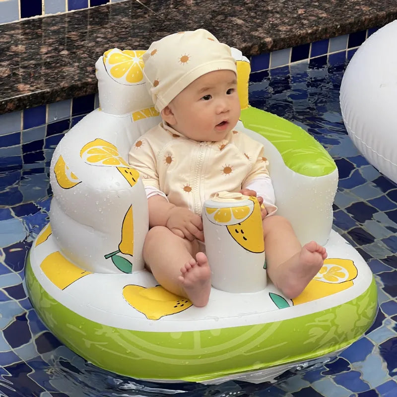 Baby in a sun hat sitting in a green fruit-print inflatable baby chair