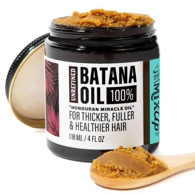 Jar of 100% batana oil hair mask with a wooden scoop